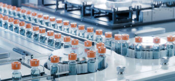 Vaccine Production Facility. Medication Manufacturing Process. Glass Vials with Orange Caps on Conveyor Belt. Medical Ampoule Production Line at Modern Pharmaceutical Factory.